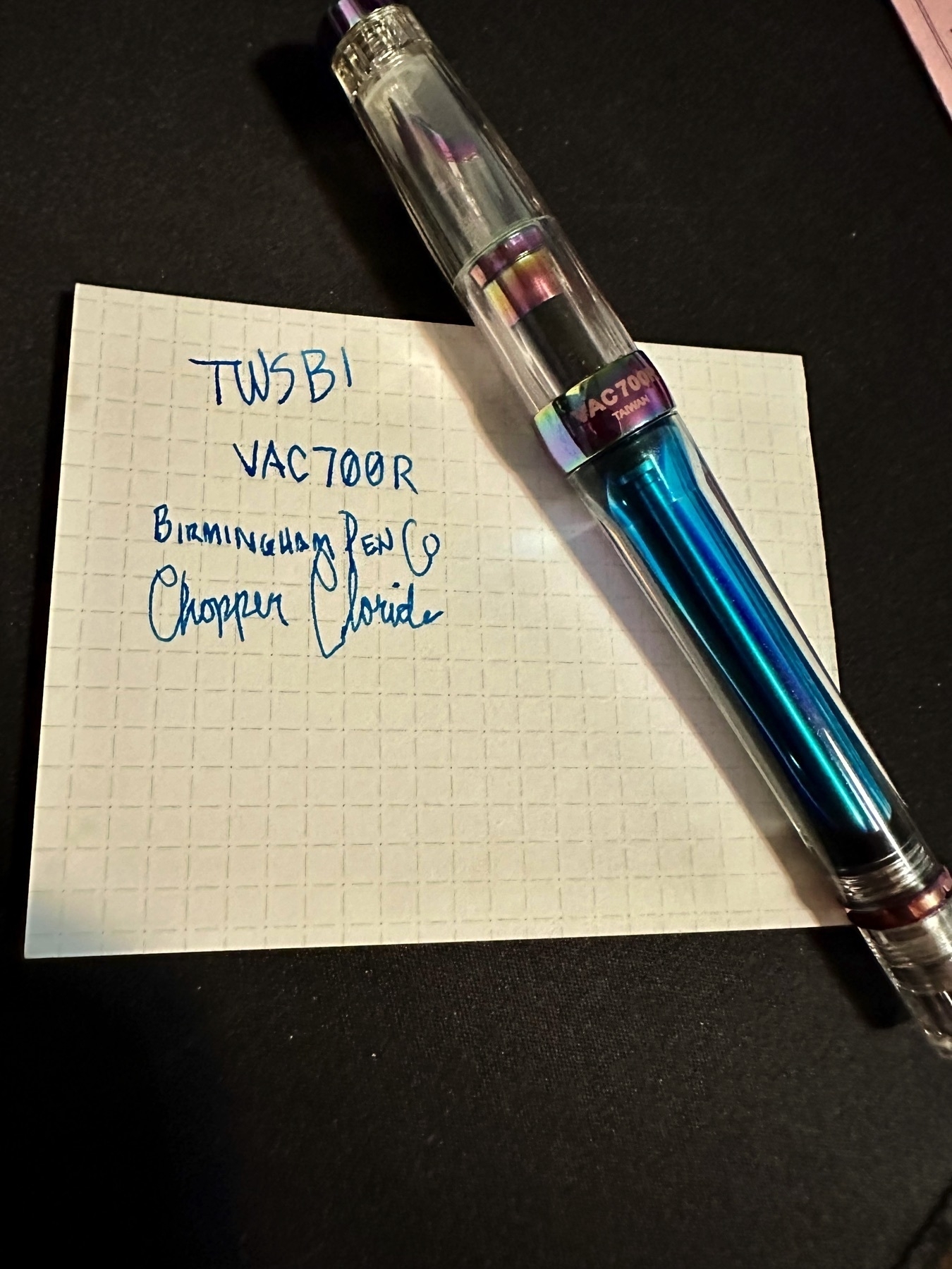 A TWSBI 700R capped. Showing off the ink inside. In the background is a card that says “TWSBI VAC700R with Birmington Pen Co Copper Choride.”